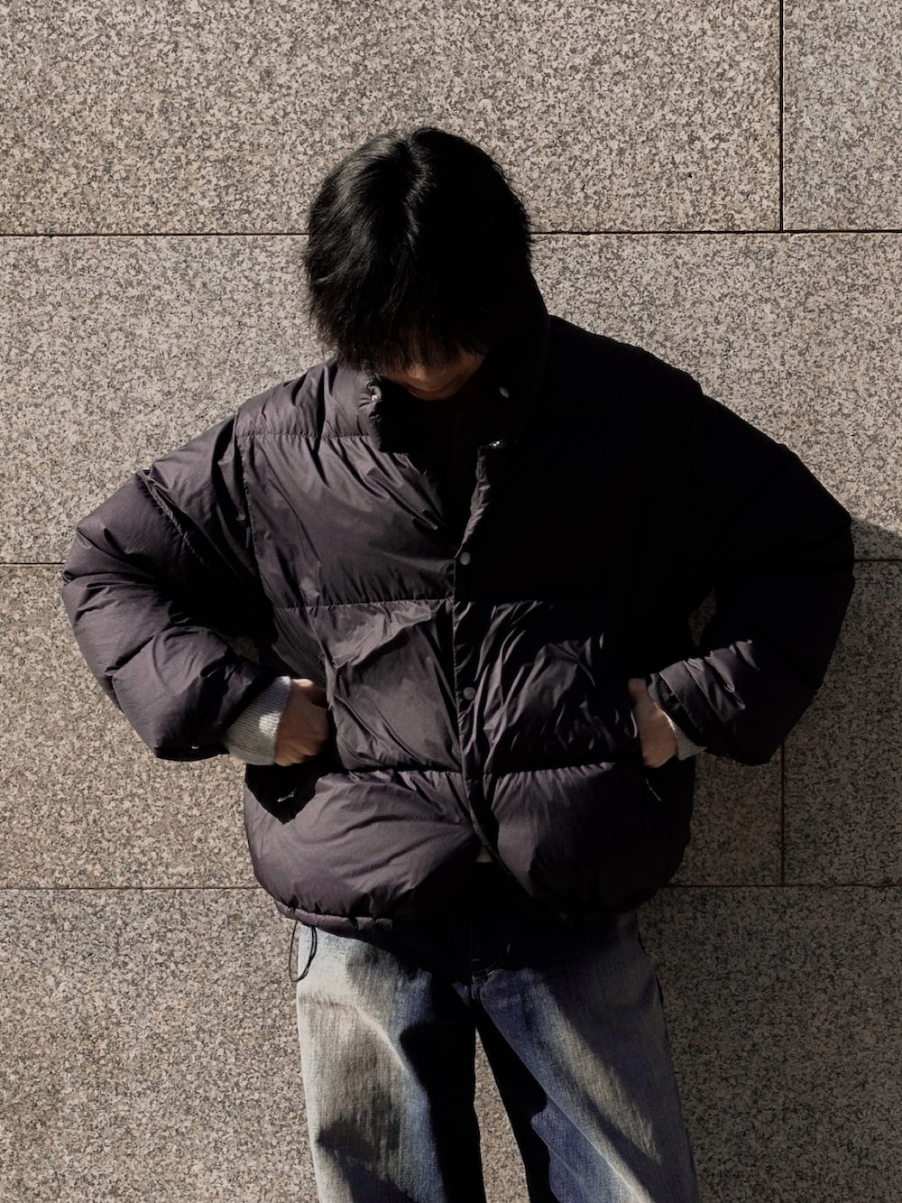 ブラック系のドレスシューズ、ブルー系のデニムパンツ、ブラック系のダウンジャケット/コートを着用したメンズの冬コーディネートの2枚目の写真