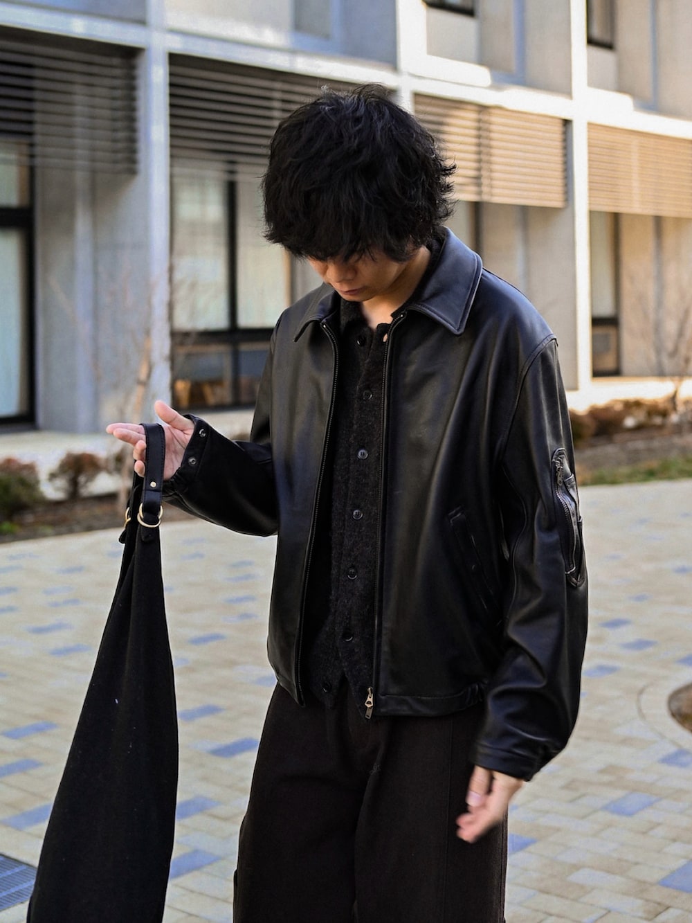 ブラック系のスニーカー、ブラック系のカーディガン/ボレロ、ブラック系のブルゾンを着用したメンズの春コーディネートの2枚目の写真