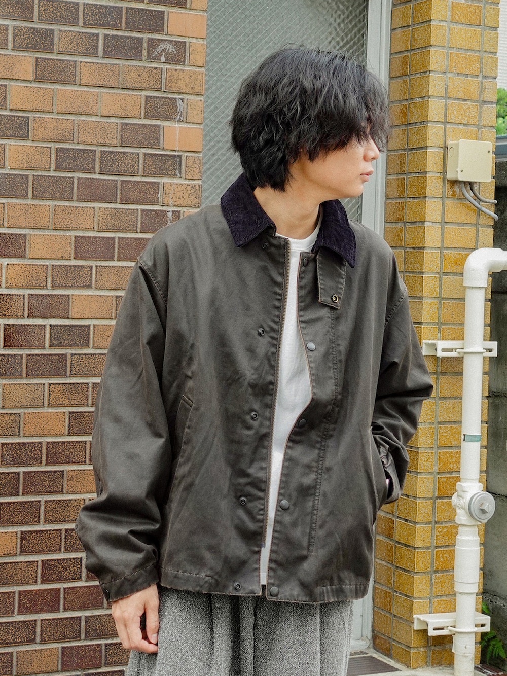 ホワイト系のTシャツ/カットソー、ブラウン系のブルゾン、グレー系のスラックスを着用したメンズの秋コーディネートの3枚目の写真