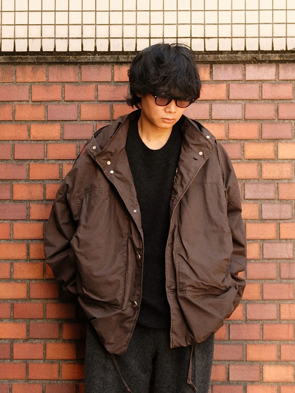 ブラウン系のブルゾン、ブラック系のニット/セーター、グレー系のスラックスを着用したメンズの冬コーディネートの2枚目の写真