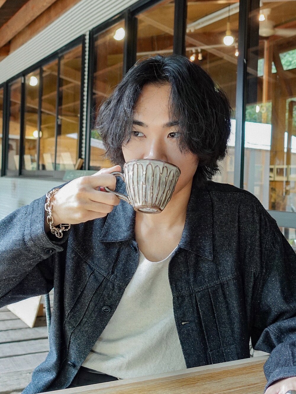 ホワイト系のタンクトップ、ブラック系のデニムジャケット、ブラック系のスラックスを着用したメンズの秋コーディネートの2枚目の写真