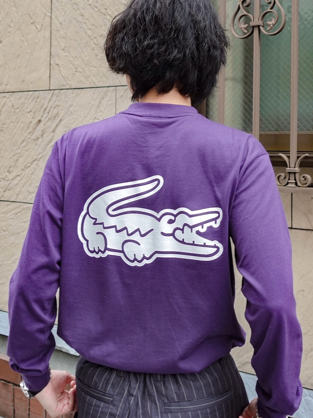 パープル系のTシャツ/カットソー、グレー系のスラックス、ブラック系のアナログ腕時計を着用したメンズの秋コーディネートの3枚目の写真