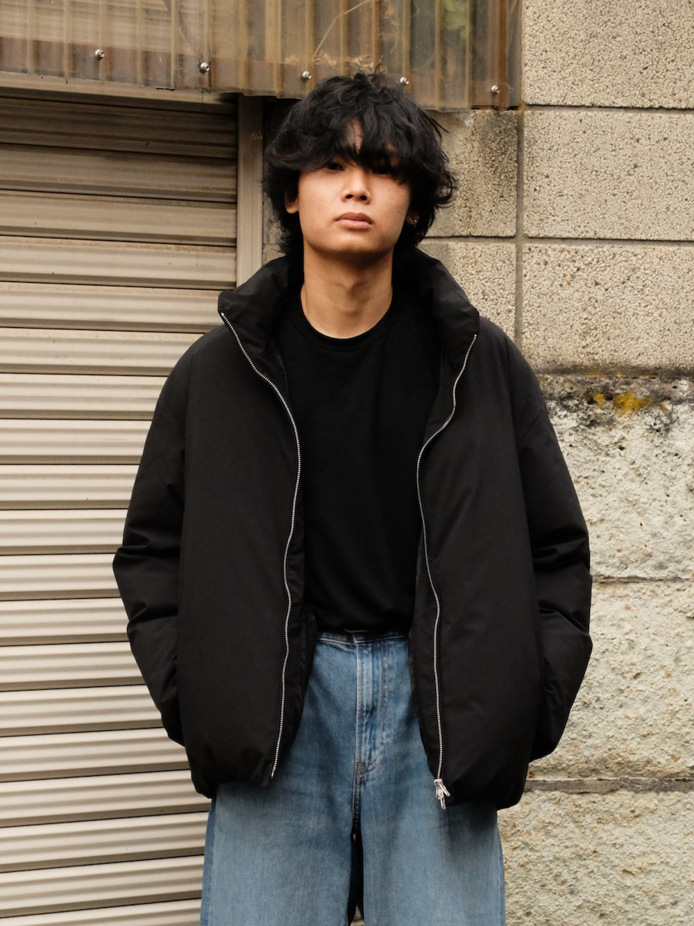 ブルー系のデニムパンツ、ブラック系のダウンジャケット/コート、ブラック系のTシャツ/カットソーを着用したメンズの冬コーディネートの2枚目の写真