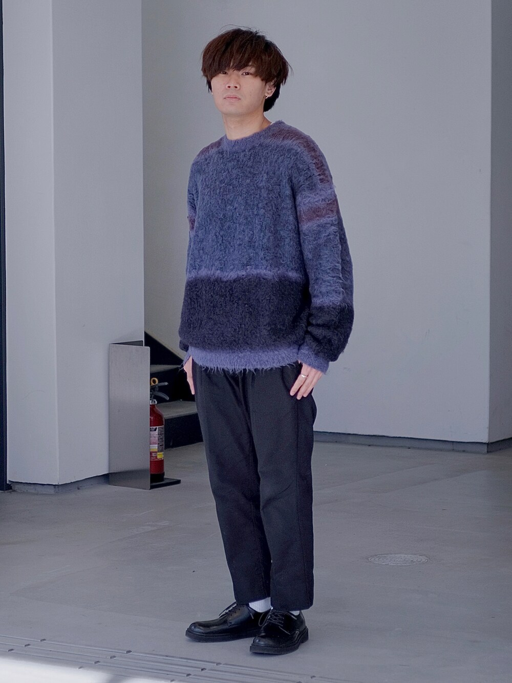 ブラック系のスラックス、ブラック系のドレスシューズ、ブルー系のニット/セーターを着用したメンズの冬コーディネートの2枚目の写真