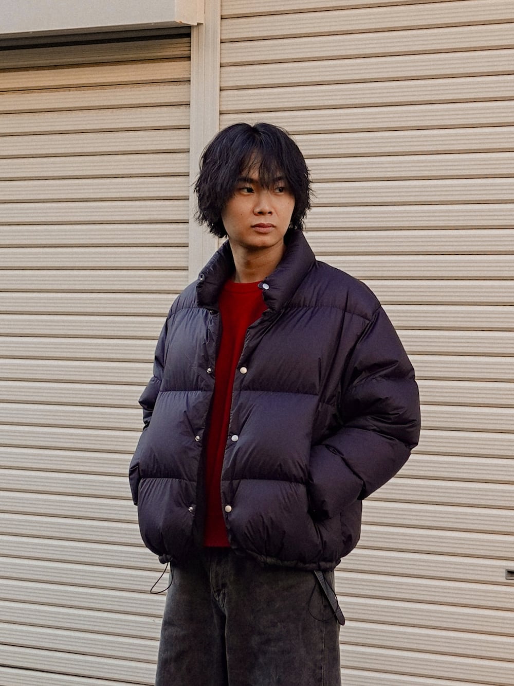 ブラック系のデニムパンツ、ブラック系のスニーカー、レッド系のニット/セーターを着用したメンズの冬コーディネートの2枚目の写真