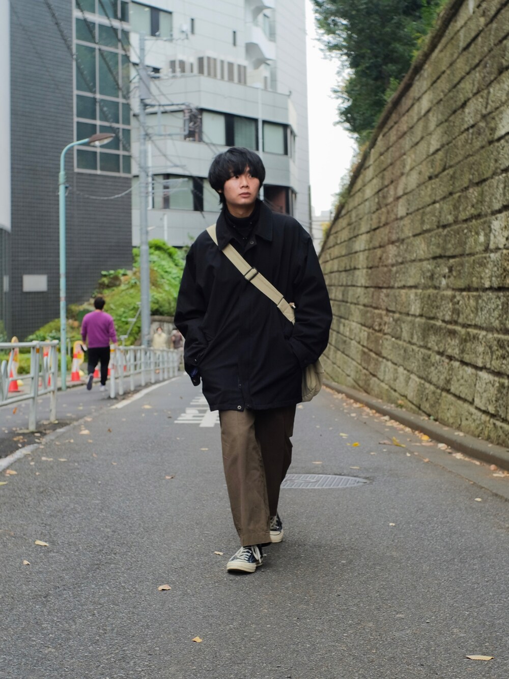 ブラック系のマウンテンパーカー、ブラック系のミリタリージャケット、ベージュ系のメッセンジャーバッグを着用したメンズの冬コーディネートの4枚目の写真