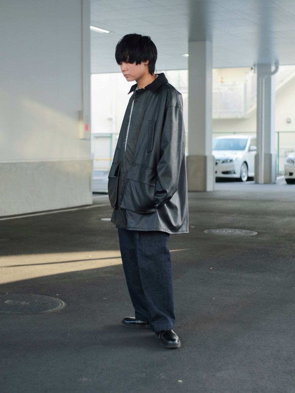 ブラック系のミリタリージャケット、グレー系のニット/セーター、ブルー系のデニムパンツを着用したメンズの冬コーディネートの5枚目の写真