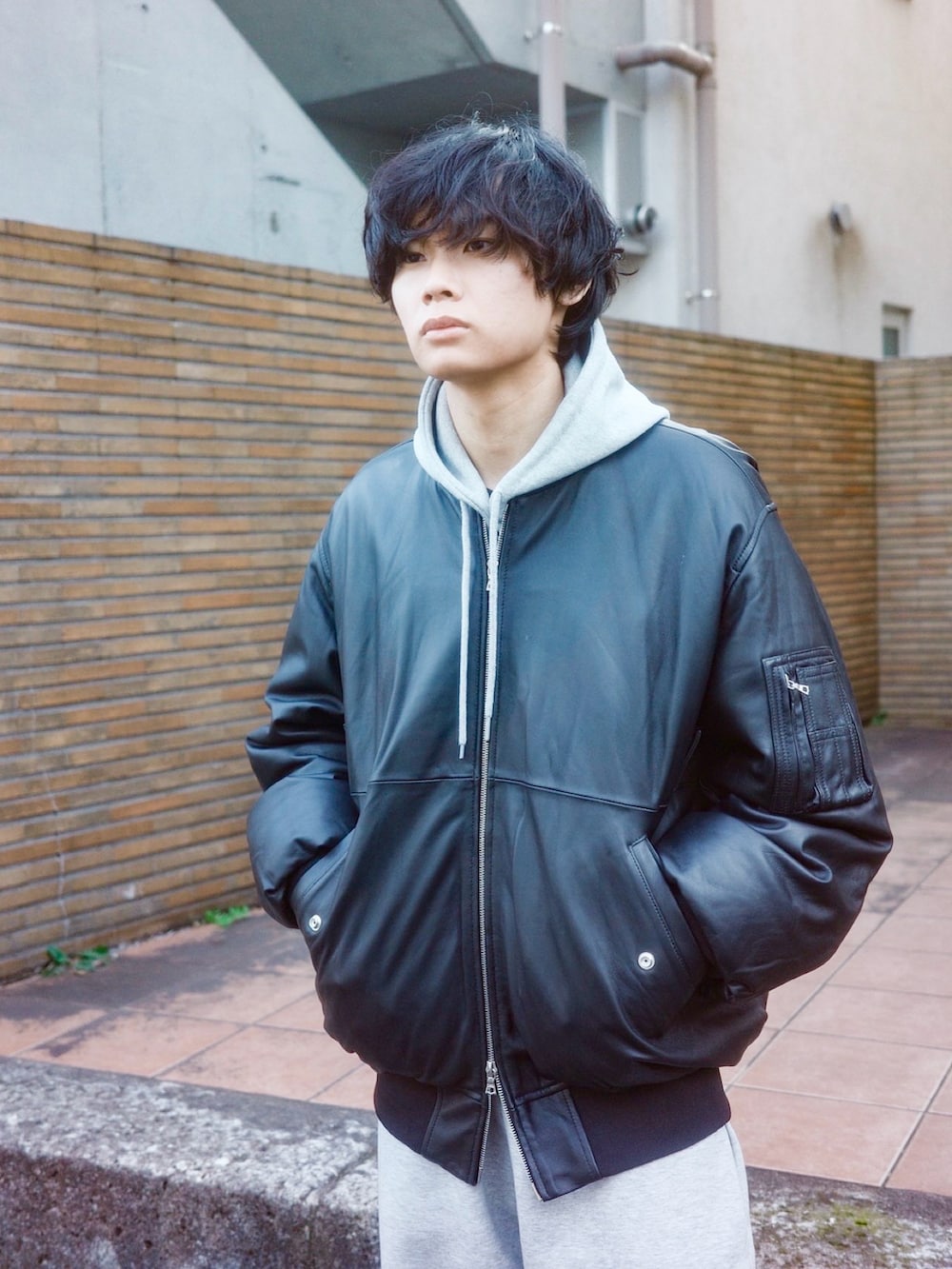 ブラック系のブルゾン、グレー系のパーカー、グレー系のスウェットパンツを着用したメンズの冬コーディネートの2枚目の写真