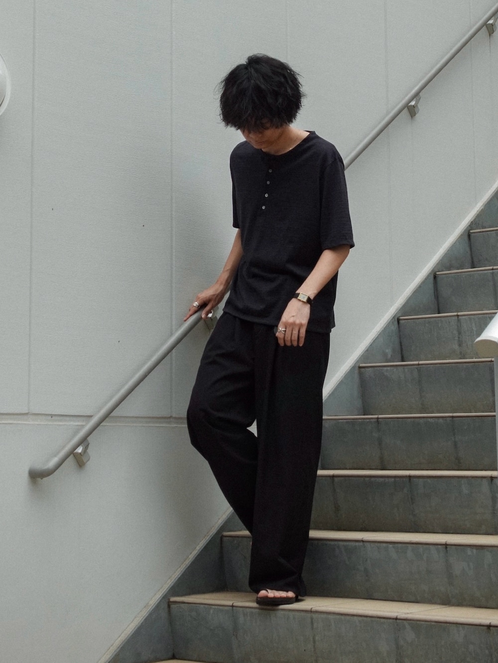 ブラック系のスラックス、ブラック系のサンダル、ブラック系のTシャツ/カットソーを着用したメンズの夏コーディネートの3枚目の写真