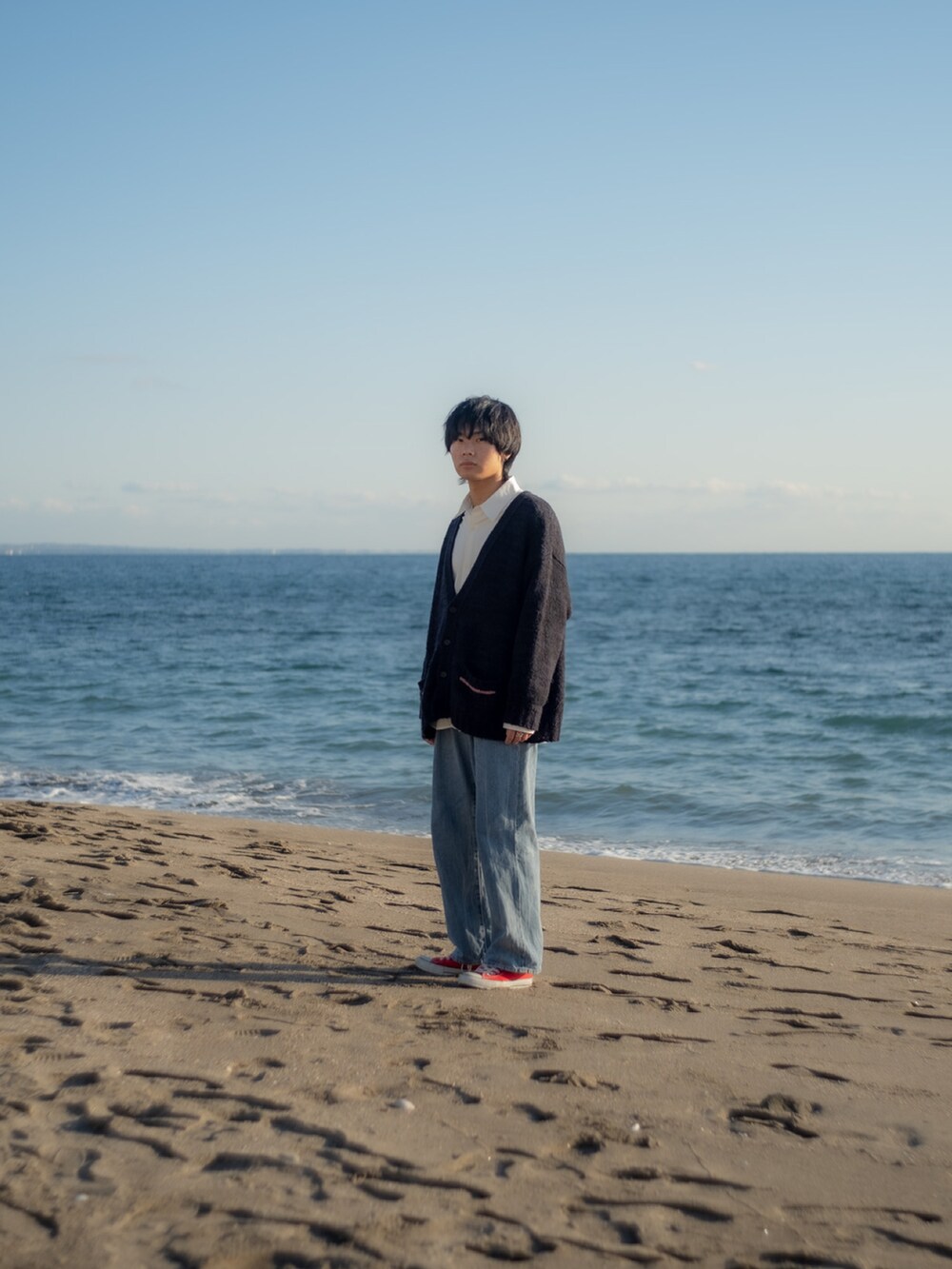 ブラック系のカーディガン/ボレロ、ホワイト系のシャツ/ブラウス、ブルー系のデニムパンツを着用したメンズの冬コーディネートの5枚目の写真