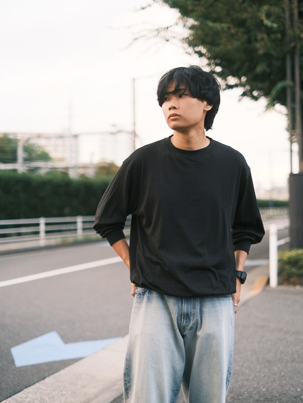 ブラック系のTシャツ/カットソー、ブラック系のスニーカー、ブルー系のデニムパンツを着用したメンズの秋コーディネートの3枚目の写真