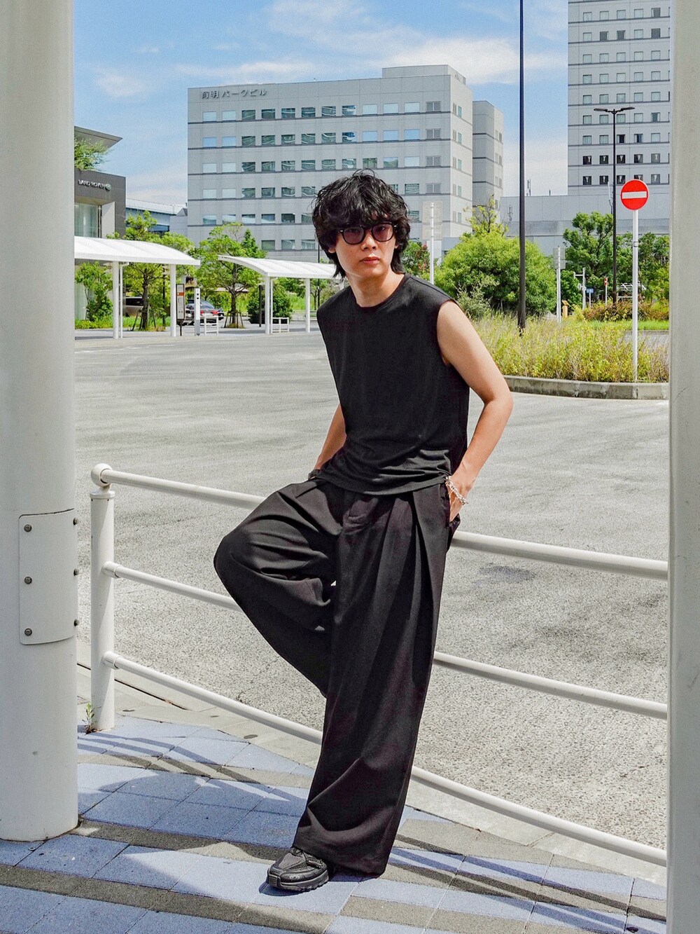 ブラック系のタンクトップ、ブラック系のスラックス、ブラック系のスニーカーを着用したメンズの夏コーディネートの2枚目の写真