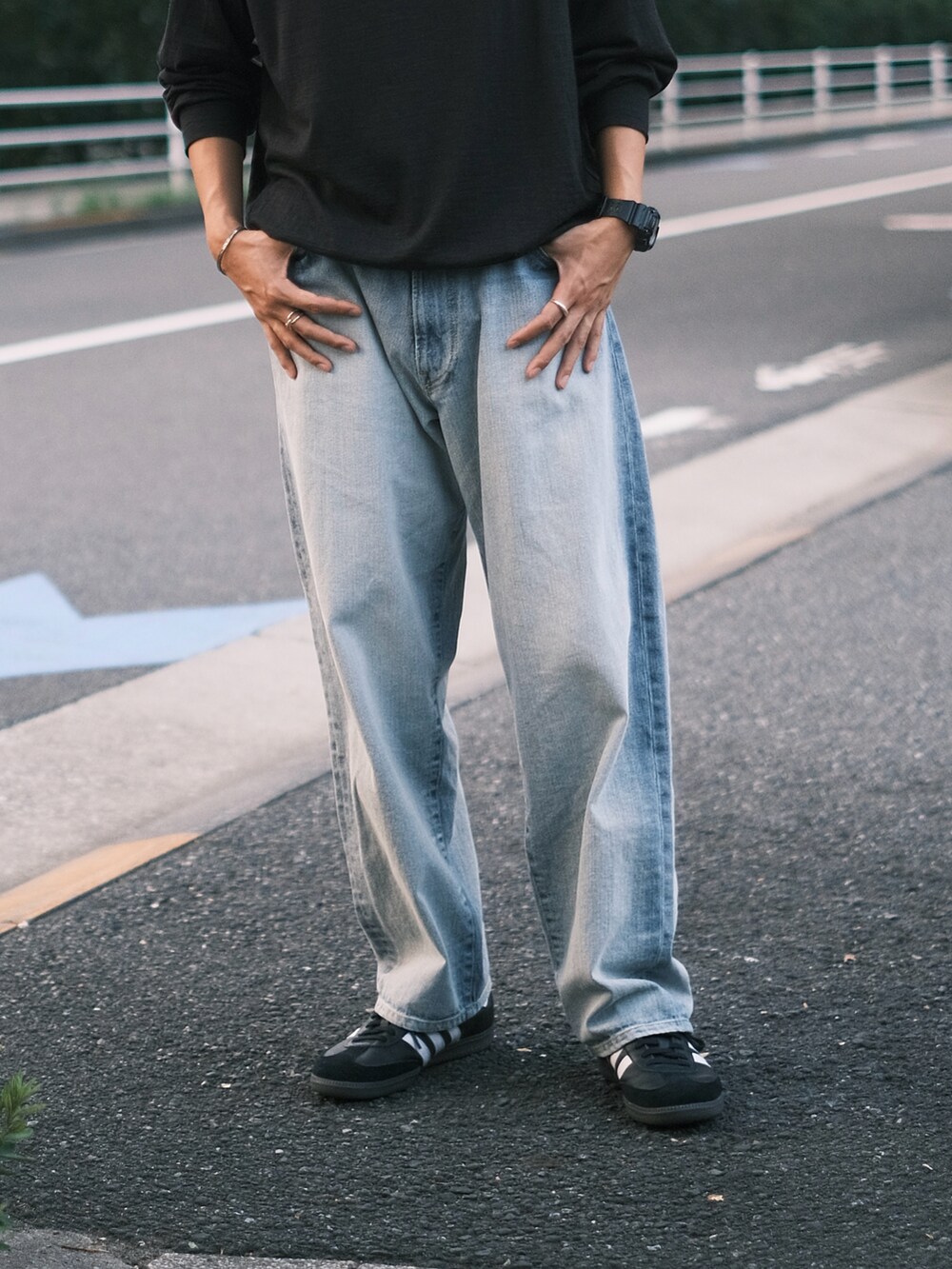 ブラック系のTシャツ/カットソー、ブラック系のスニーカー、ブルー系のデニムパンツを着用したメンズの秋コーディネートの2枚目の写真