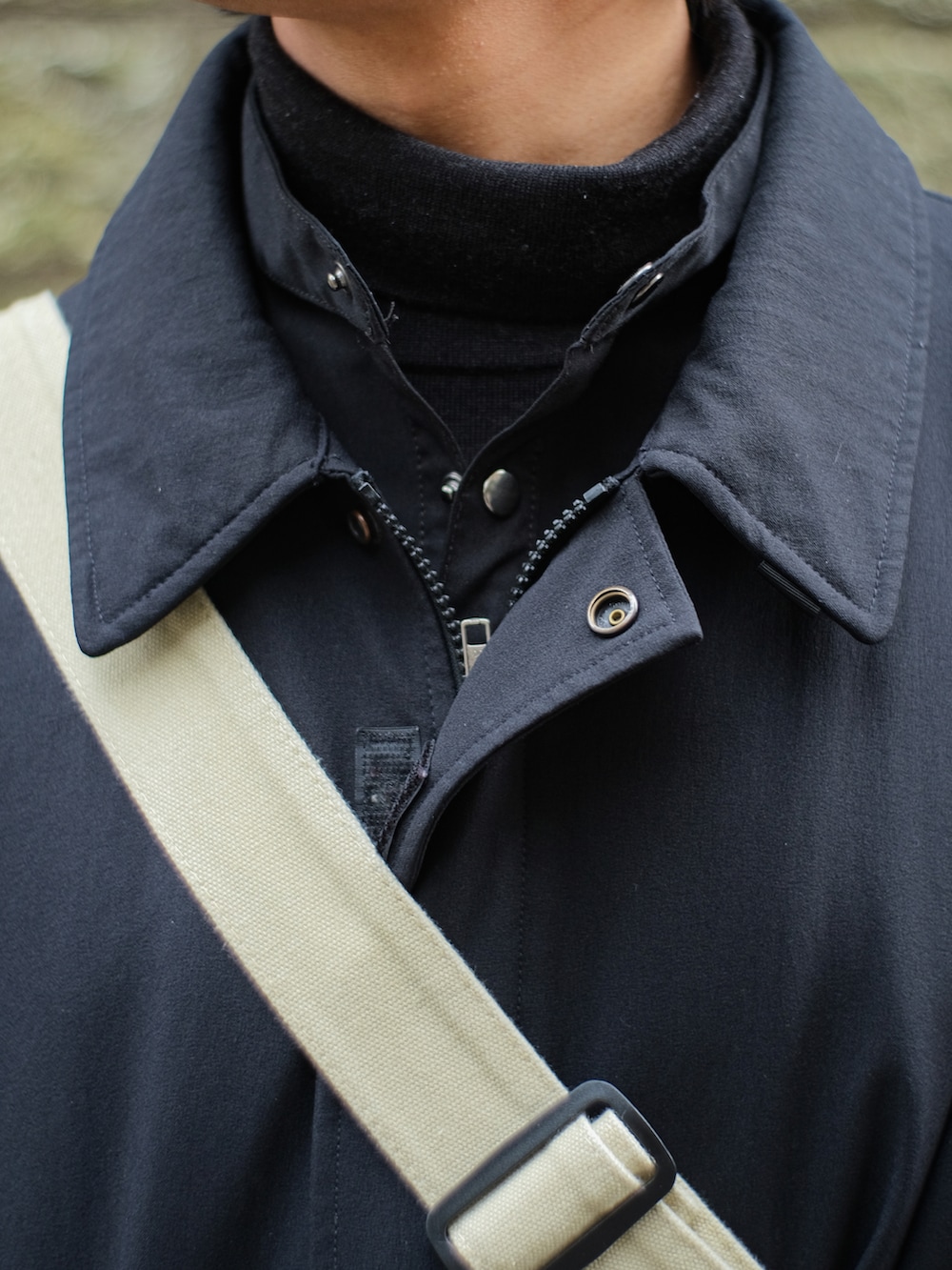 ブラック系のマウンテンパーカー、ブラック系のミリタリージャケット、ベージュ系のメッセンジャーバッグを着用したメンズの冬コーディネートの2枚目の写真