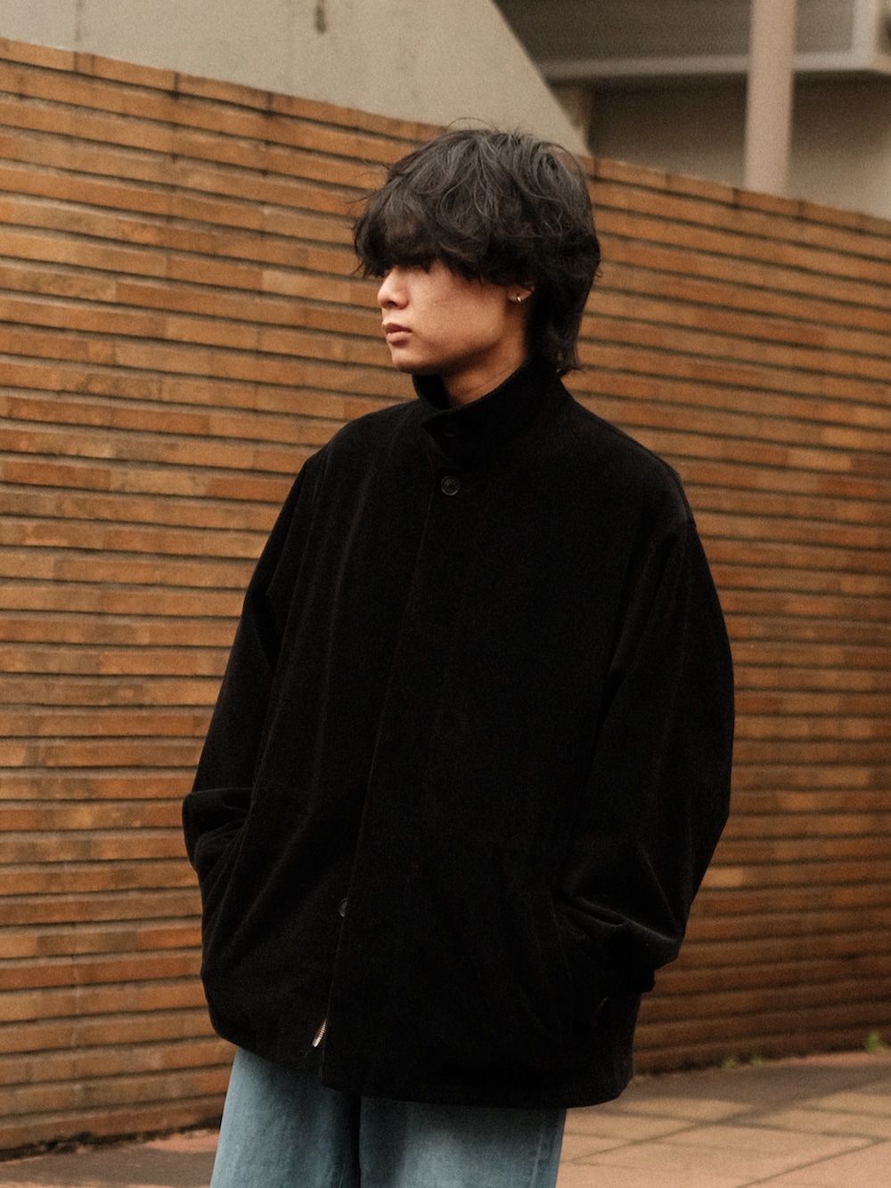 ブラック系のブルゾン、ブルー系のデニムパンツ、ブラック系のモカシン/デッキシューズを着用したメンズの冬コーディネートの2枚目の写真