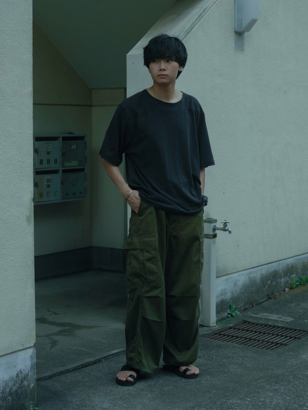 ブラック系のTシャツ/カットソー、ブラック系のバックパック/リュック、グリーン系のカーゴパンツを着用したメンズの夏コーディネートの3枚目の写真