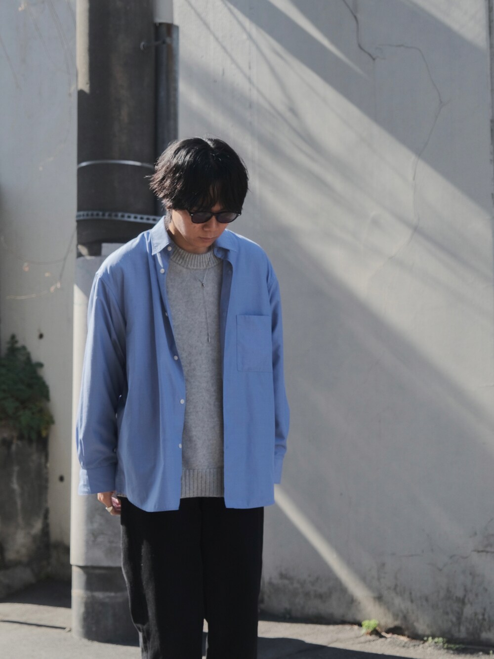 ブルー系のシャツ/ブラウス、グレー系のニット/セーター、ブラック系のデニムパンツを着用したメンズの春コーディネートの2枚目の写真