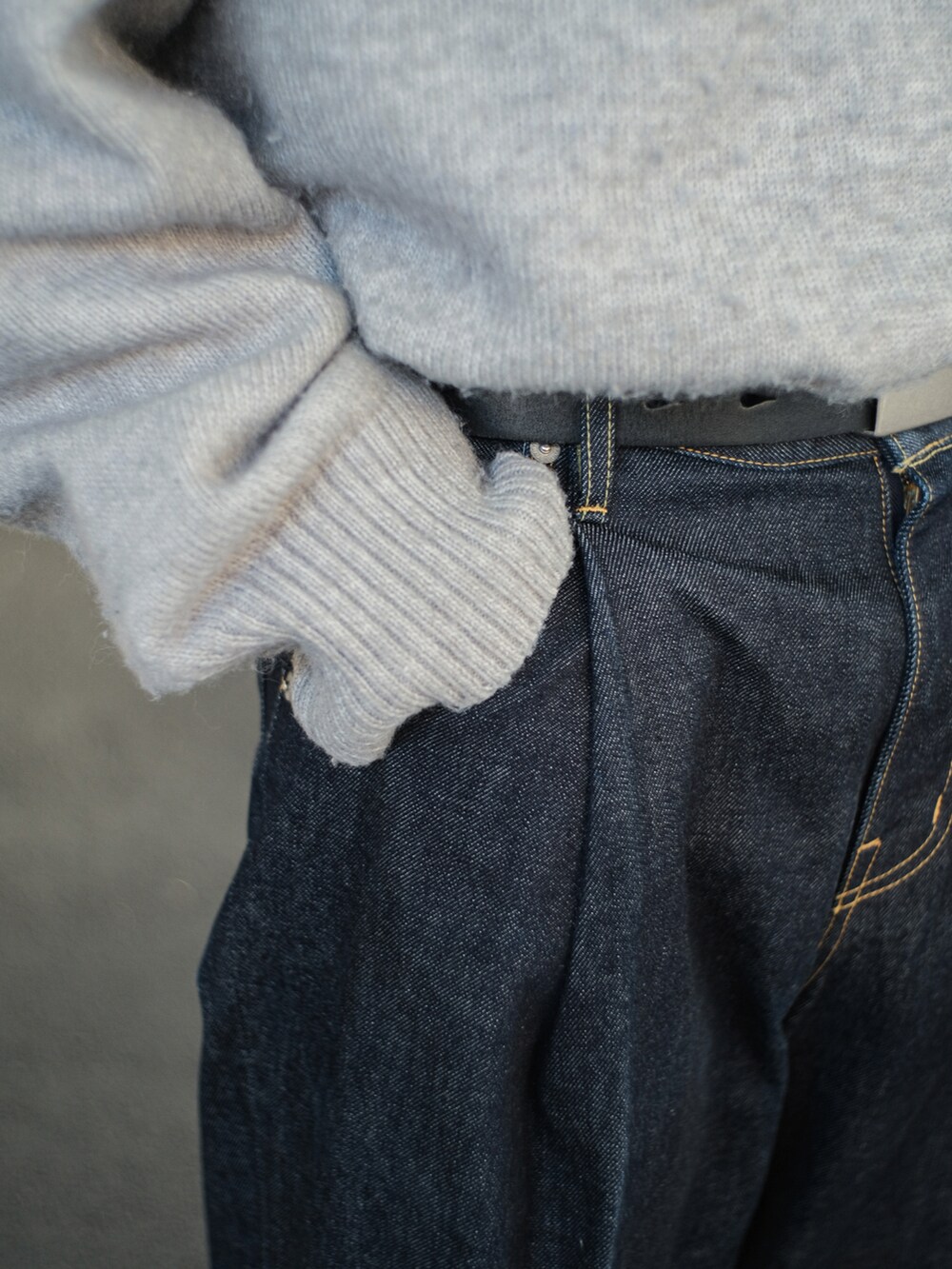 グレー系のニット/セーター、ブルー系のデニムパンツ、ブラック系のドレスシューズを着用したメンズの冬コーディネートの3枚目の写真