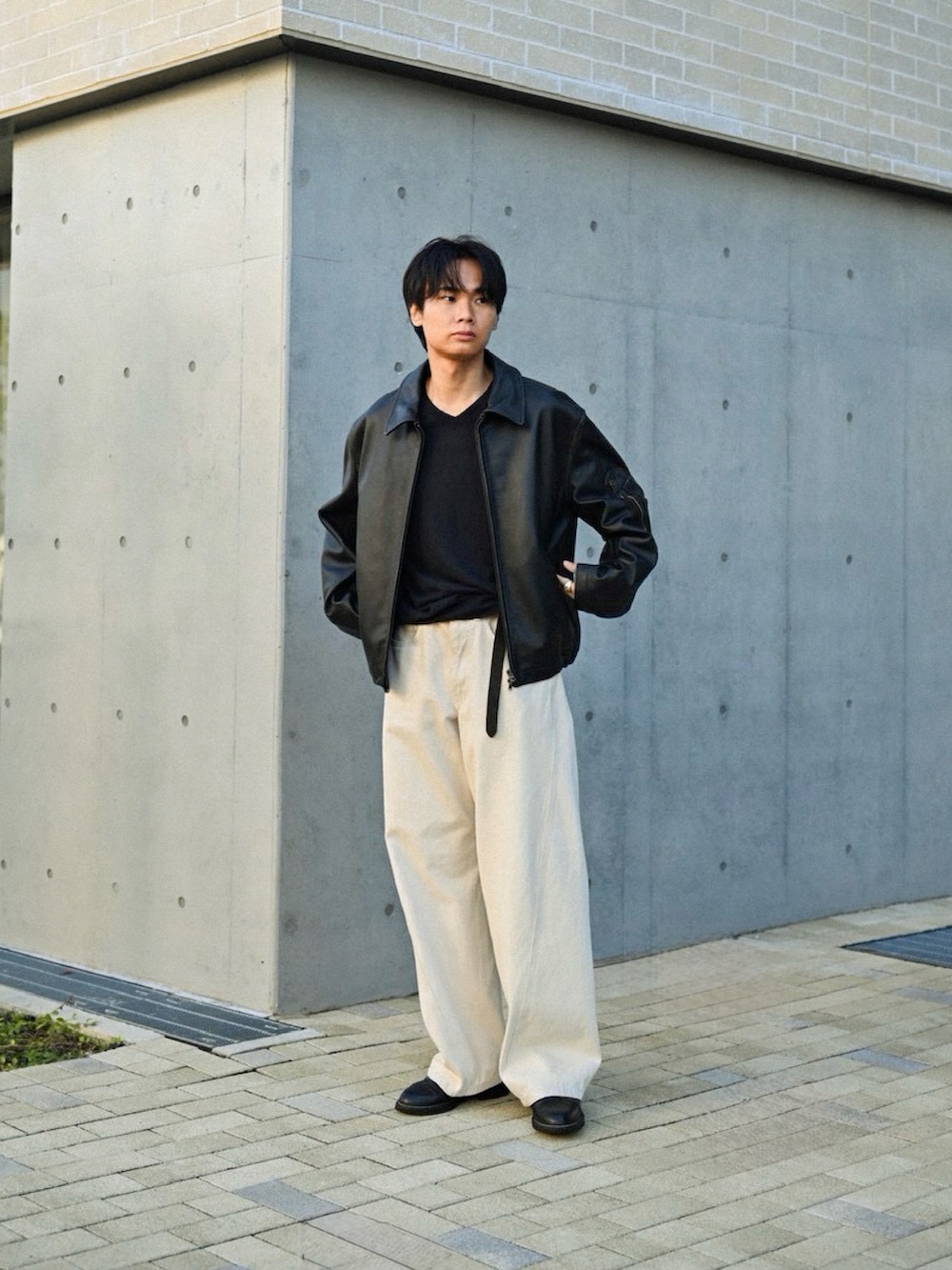 ホワイト系のデニムパンツ、ブラック系のドレスシューズ、ブラック系のブルゾンを着用したメンズの秋コーディネートの2枚目の写真