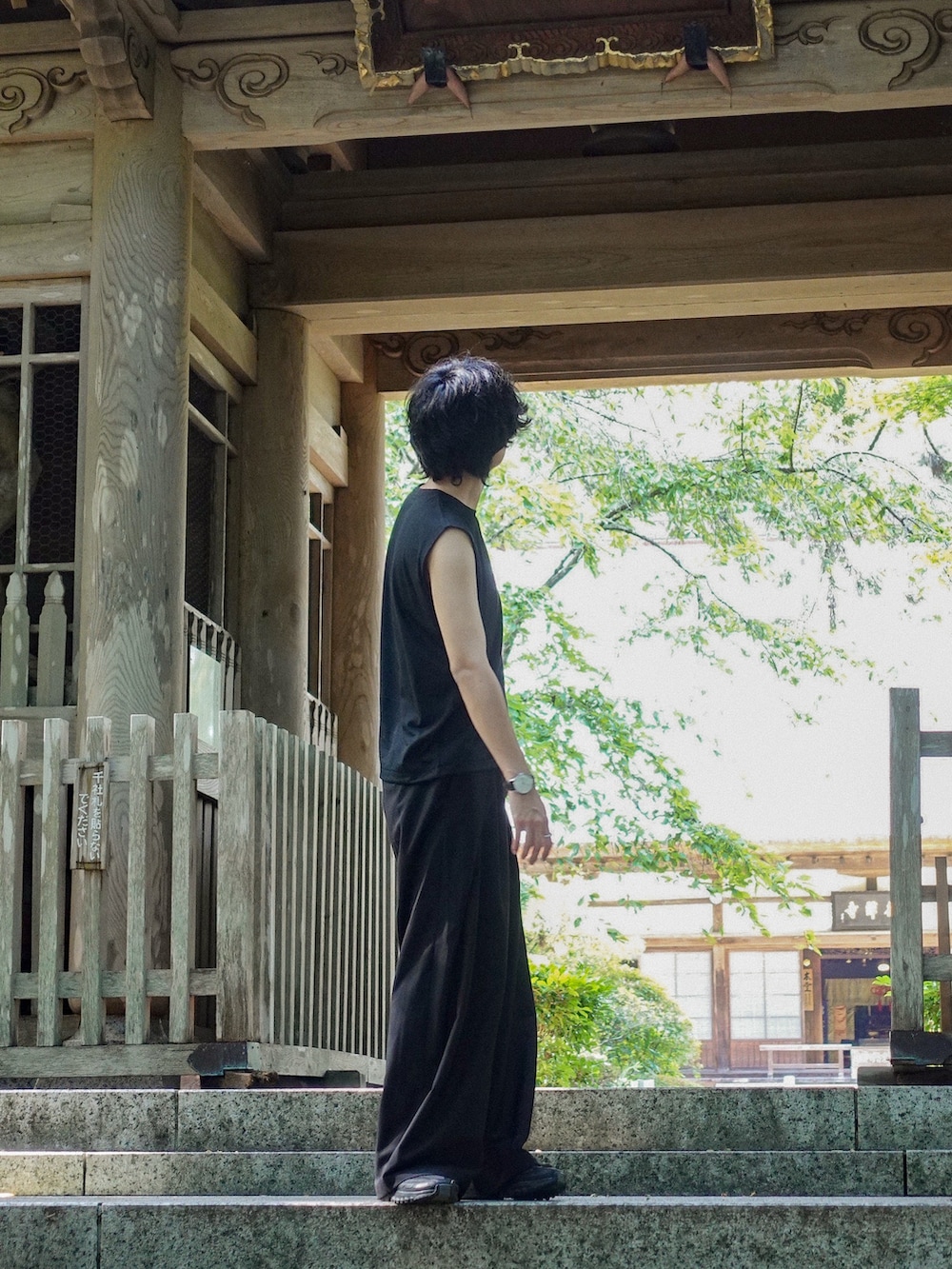 ブラック系のタンクトップ、ブラック系のスラックス、ブラック系のスニーカーを着用したメンズの夏コーディネートの2枚目の写真