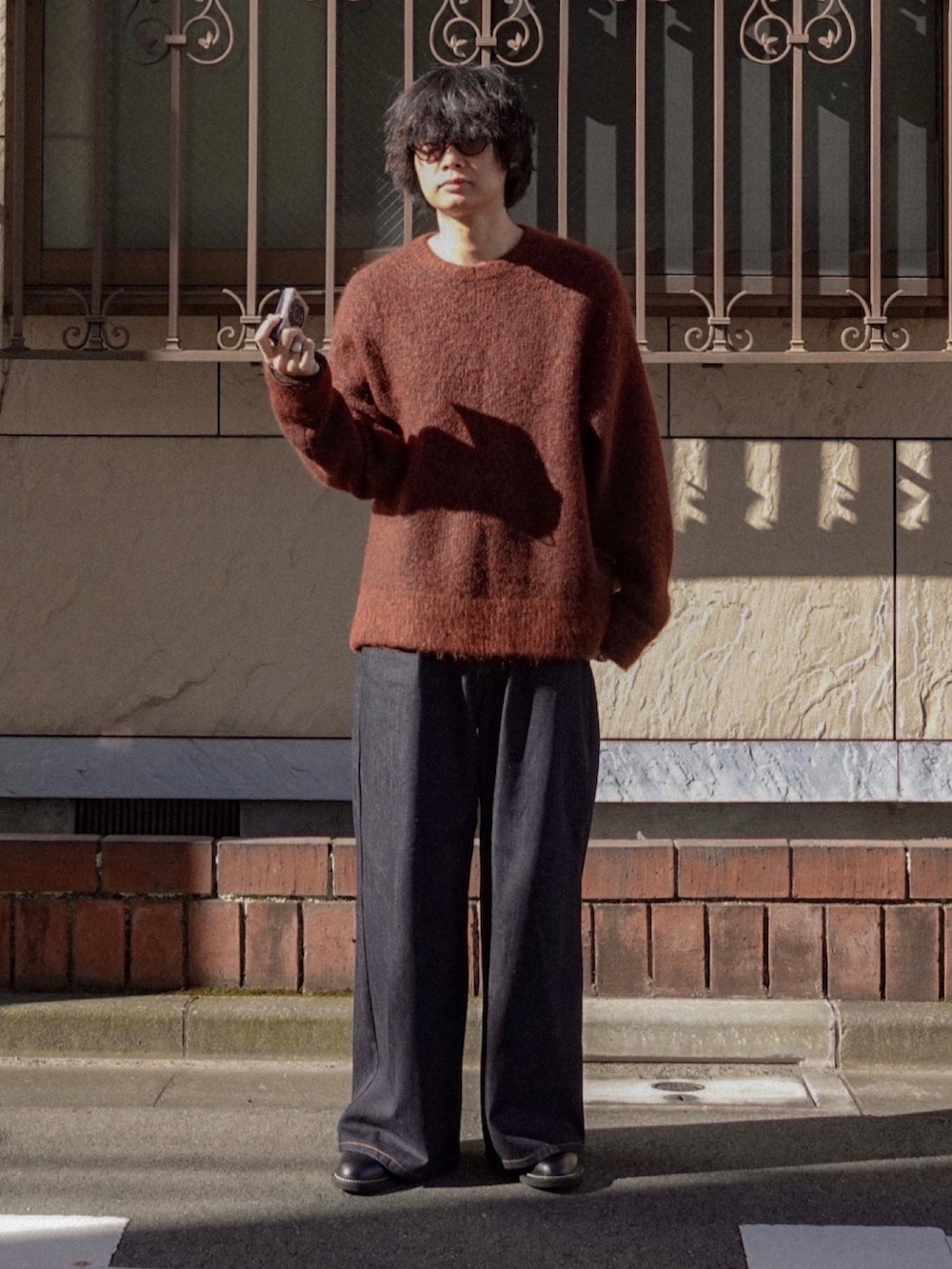 ブルー系のデニムパンツ、ブラック系のドレスシューズ、ブラウン系のニット/セーターを着用したメンズの冬コーディネートの3枚目の写真