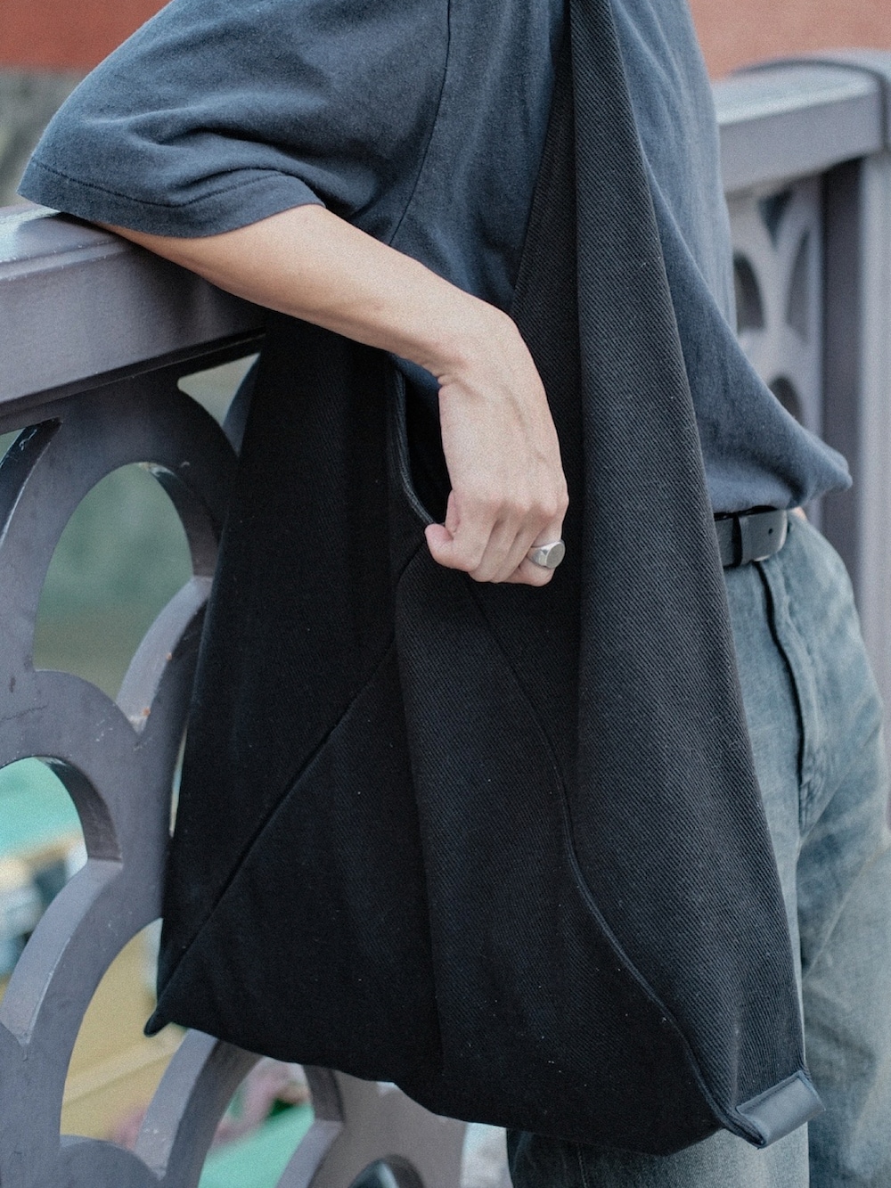 ブラック系のTシャツ/カットソー、ブラック系のトートバッグ、ブラック系のデニムパンツを着用したメンズの夏コーディネートの3枚目の写真