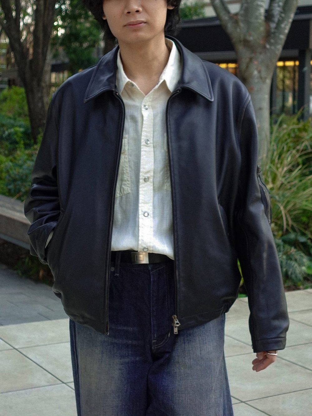 ブラック系のブーツ、ブラック系のブルゾン、ブルー系のデニムパンツを着用したメンズの春コーディネートの2枚目の写真