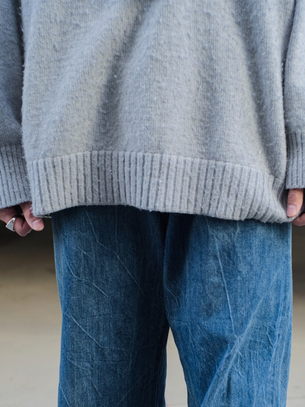 グレー系のニット/セーター、ブルー系のデニムパンツ、ブラック系のドレスシューズを着用したメンズの冬コーディネートの4枚目の写真