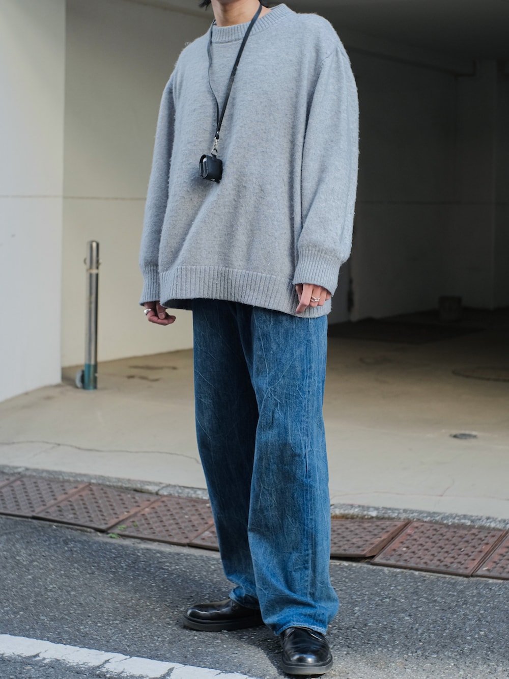 グレー系のニット/セーター、ブルー系のデニムパンツ、ブラック系のドレスシューズを着用したメンズの冬コーディネートの2枚目の写真