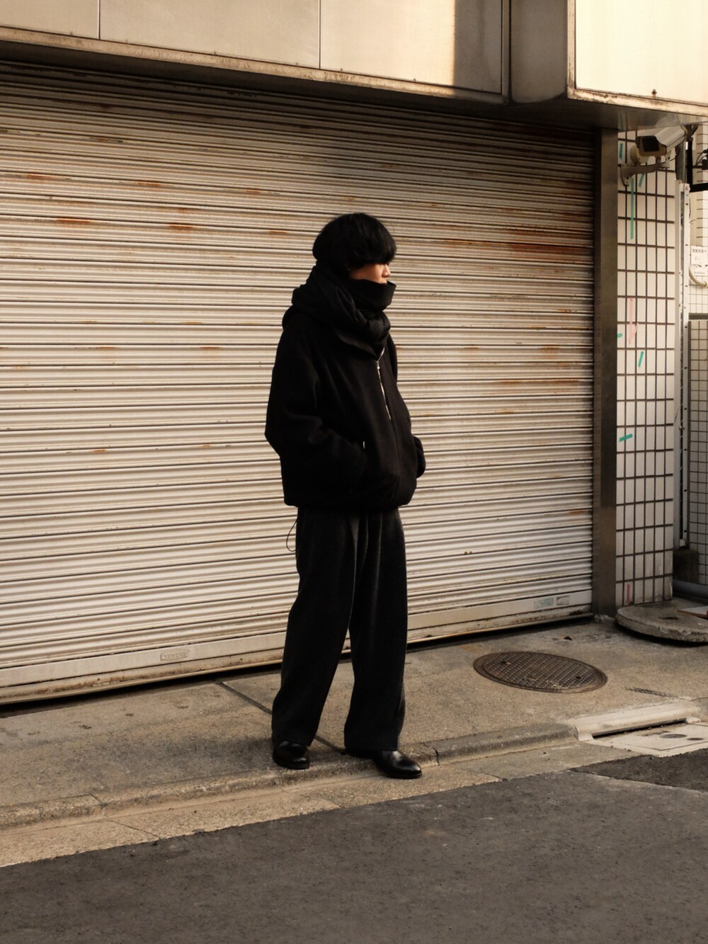 ブラック系のブルゾン、グレー系のスラックス、ブラック系のブーツを着用したメンズの冬コーディネートの2枚目の写真