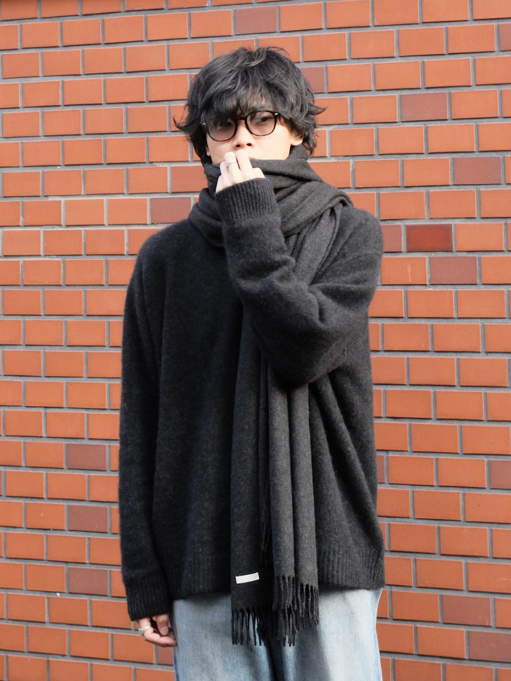 ブラック系のニット/セーター、ブルー系のデニムパンツ、ブラック系のブーツを着用したメンズの冬コーディネートの2枚目の写真