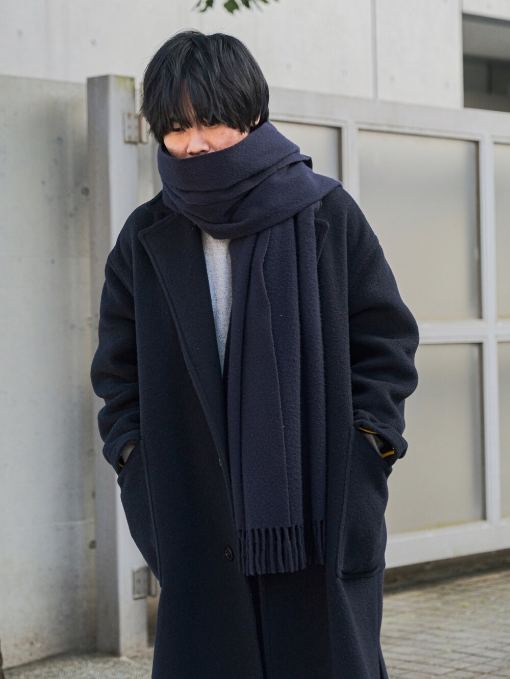 ブルー系のチェスターコート、ブルー系のデニムパンツ、ブラック系のドレスシューズを着用したメンズの冬コーディネートの3枚目の写真