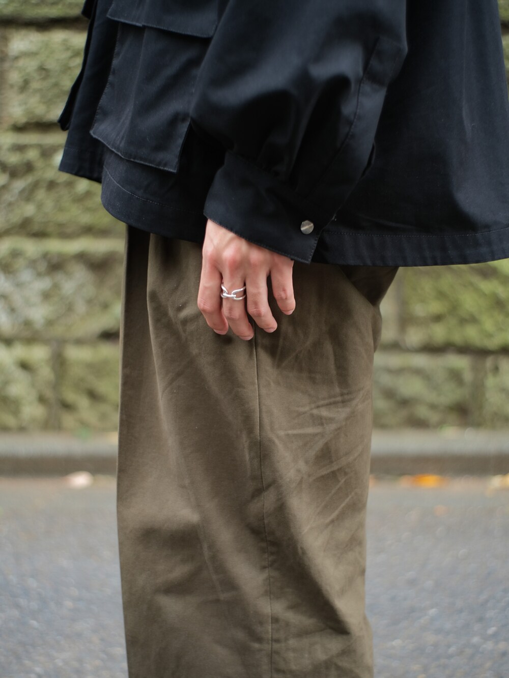 ブラック系のマウンテンパーカー、ブラック系のミリタリージャケット、ベージュ系のメッセンジャーバッグを着用したメンズの冬コーディネートの5枚目の写真