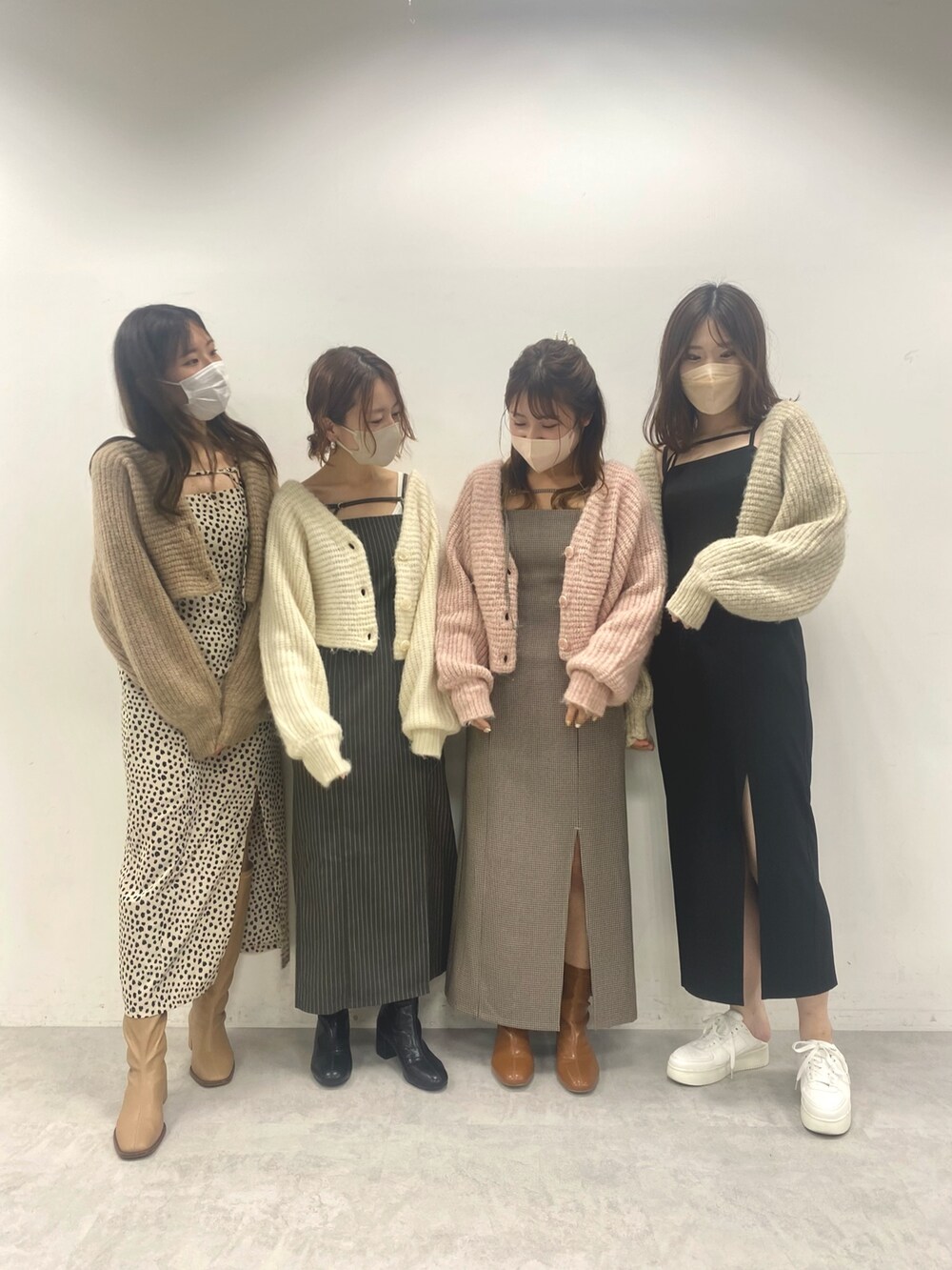 グレー系のワンピース、ホワイト系のカーディガン/ボレロ、ブラック系のブーツを着用したレディースの秋コーディネートの2枚目の写真