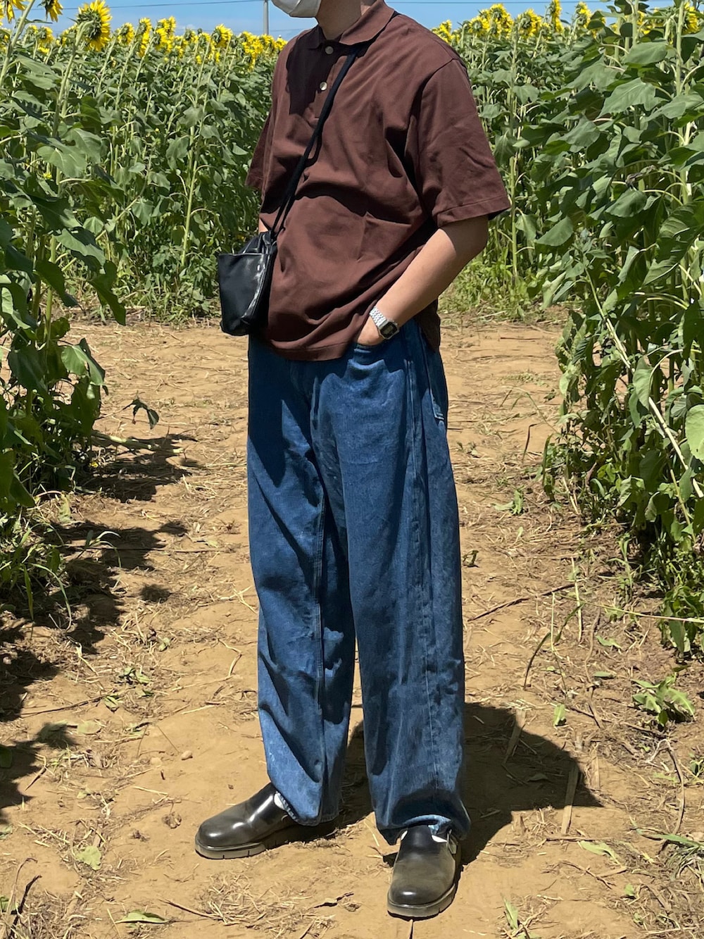 ブラウン系のポロシャツ、ブルー系のデニムパンツ、ブラック系のサンダルを着用したメンズの夏コーディネートの2枚目の写真