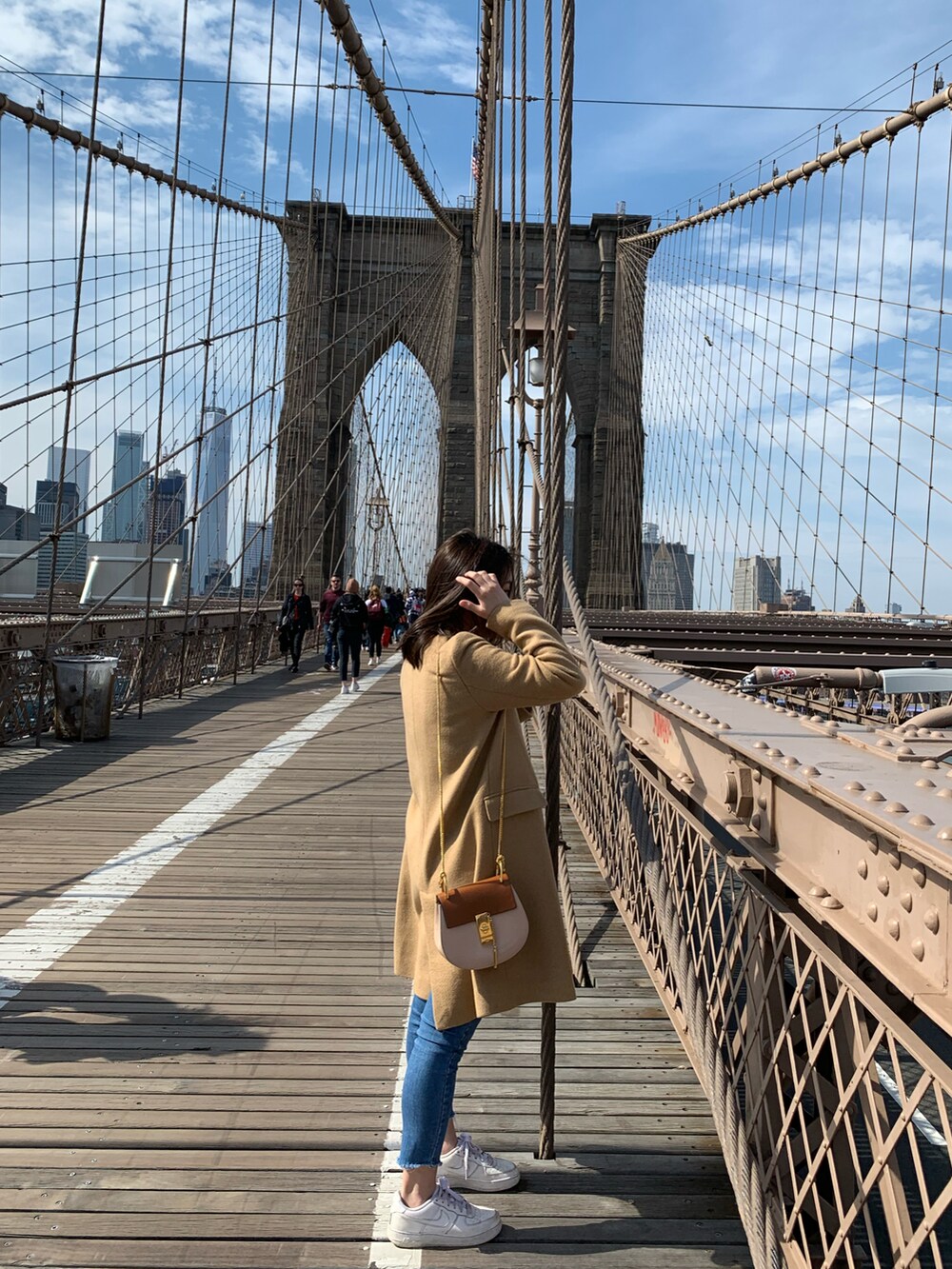 ベージュ系のチェスターコート、ブラック系のTシャツ/カットソー、ブルー系のデニムパンツを着用したレディースの秋コーディネートの2枚目の写真