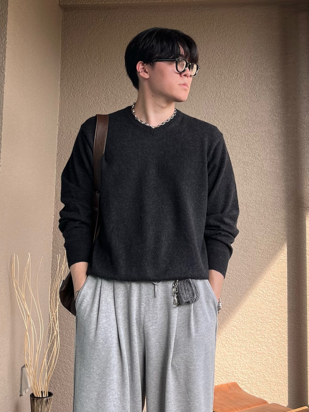 ブラウン系のショルダーバッグ、グレー系のニット/セーター、グレー系のスウェットパンツを着用したメンズの秋コーディネートの2枚目の写真