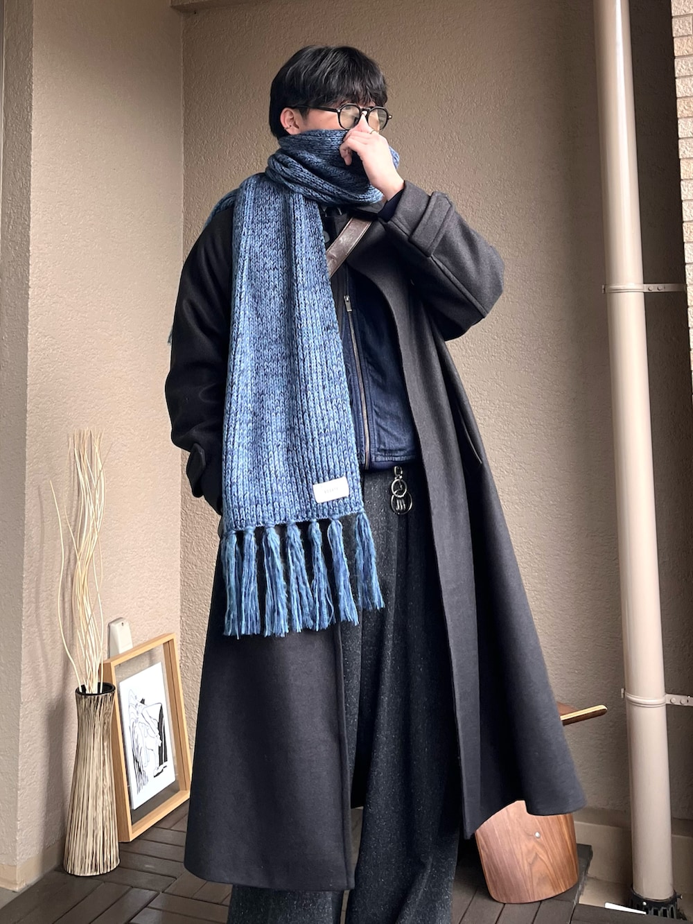 ブラウン系のショルダーバッグ、ブラック系のステンカラーコート、ブルー系のデニムジャケットを着用したメンズの冬コーディネートの2枚目の写真