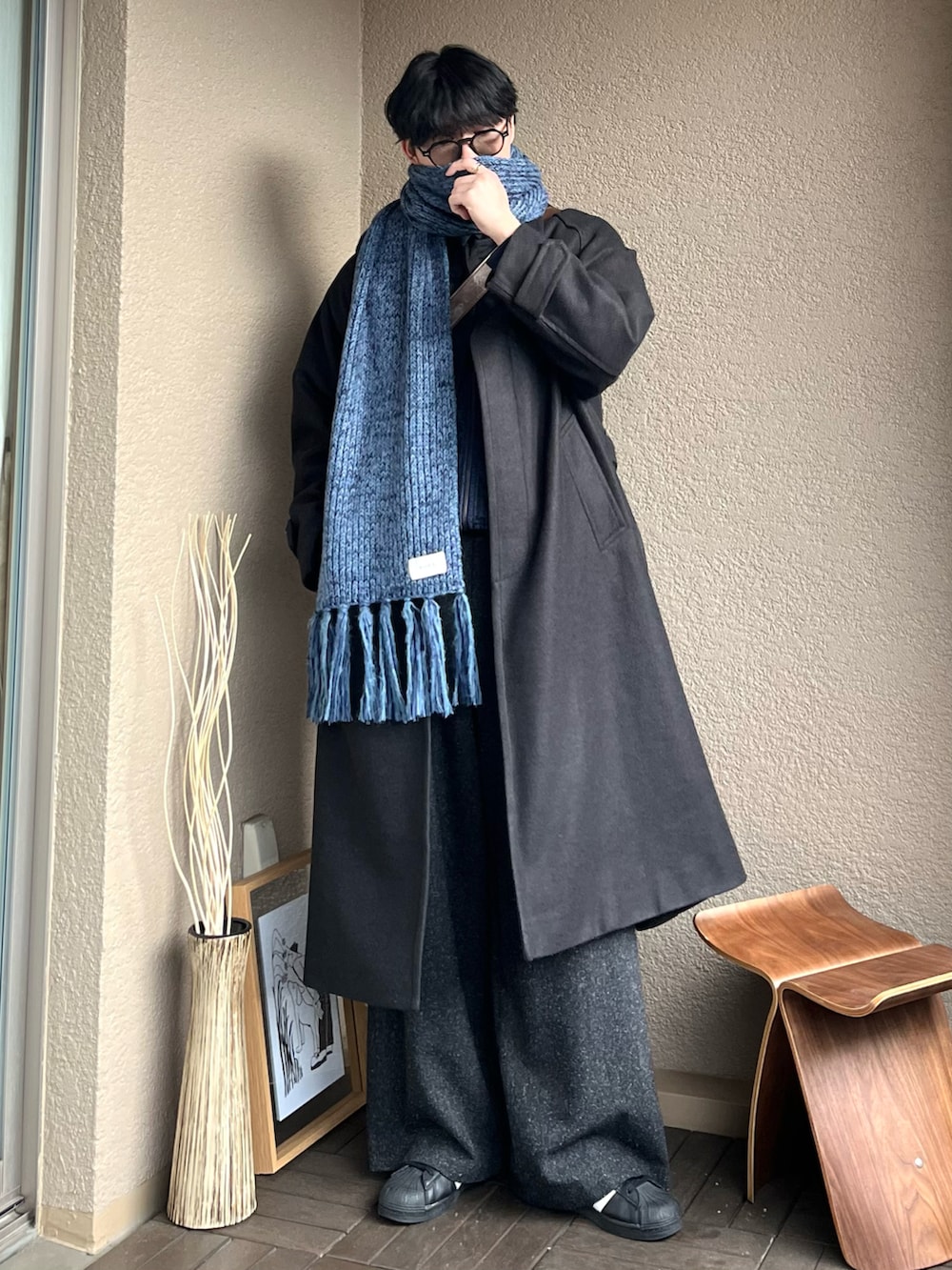 ブラウン系のショルダーバッグ、ブラック系のステンカラーコート、ブルー系のデニムジャケットを着用したメンズの冬コーディネートの3枚目の写真