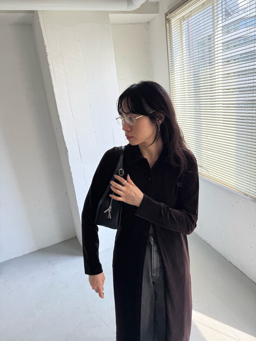 ブラック系のデニムパンツ、ブラウン系のワンピース、ブラック系のボストンバッグを着用したレディースの秋コーディネートの6枚目の写真