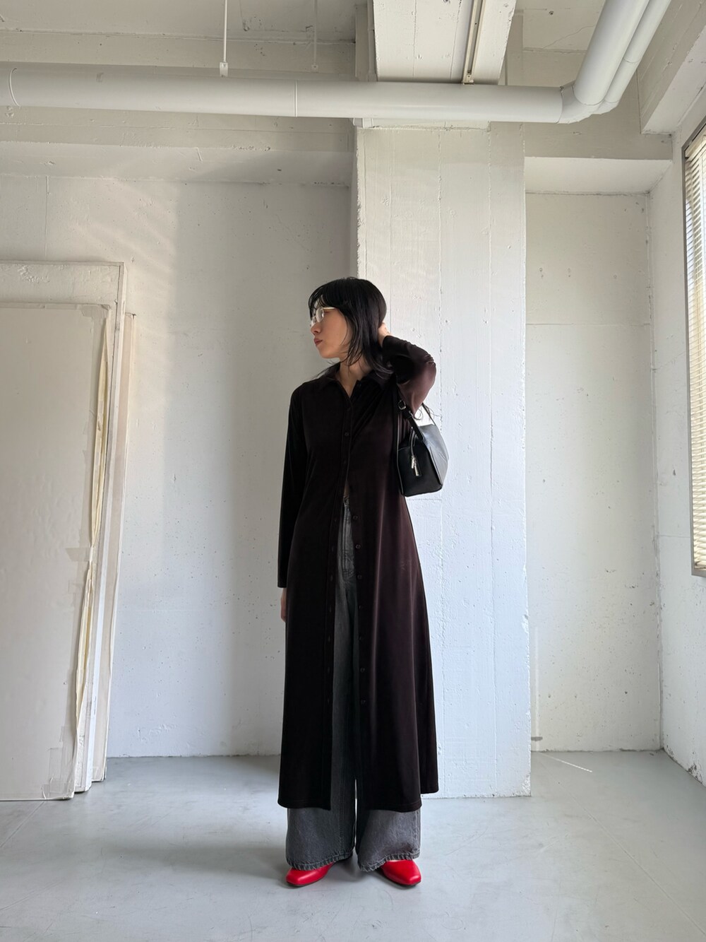 ブラック系のデニムパンツ、ブラウン系のワンピース、ブラック系のボストンバッグを着用したレディースの秋コーディネートの5枚目の写真