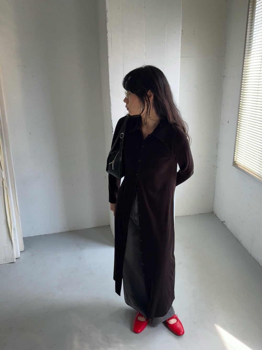 ブラック系のデニムパンツ、ブラウン系のワンピース、ブラック系のボストンバッグを着用したレディースの秋コーディネートの3枚目の写真