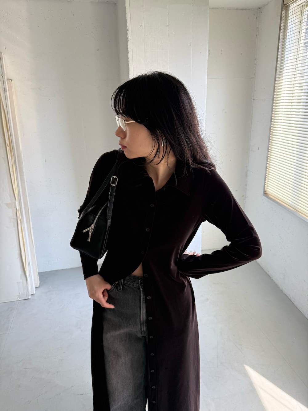 ブラック系のデニムパンツ、ブラウン系のワンピース、ブラック系のボストンバッグを着用したレディースの秋コーディネートの2枚目の写真