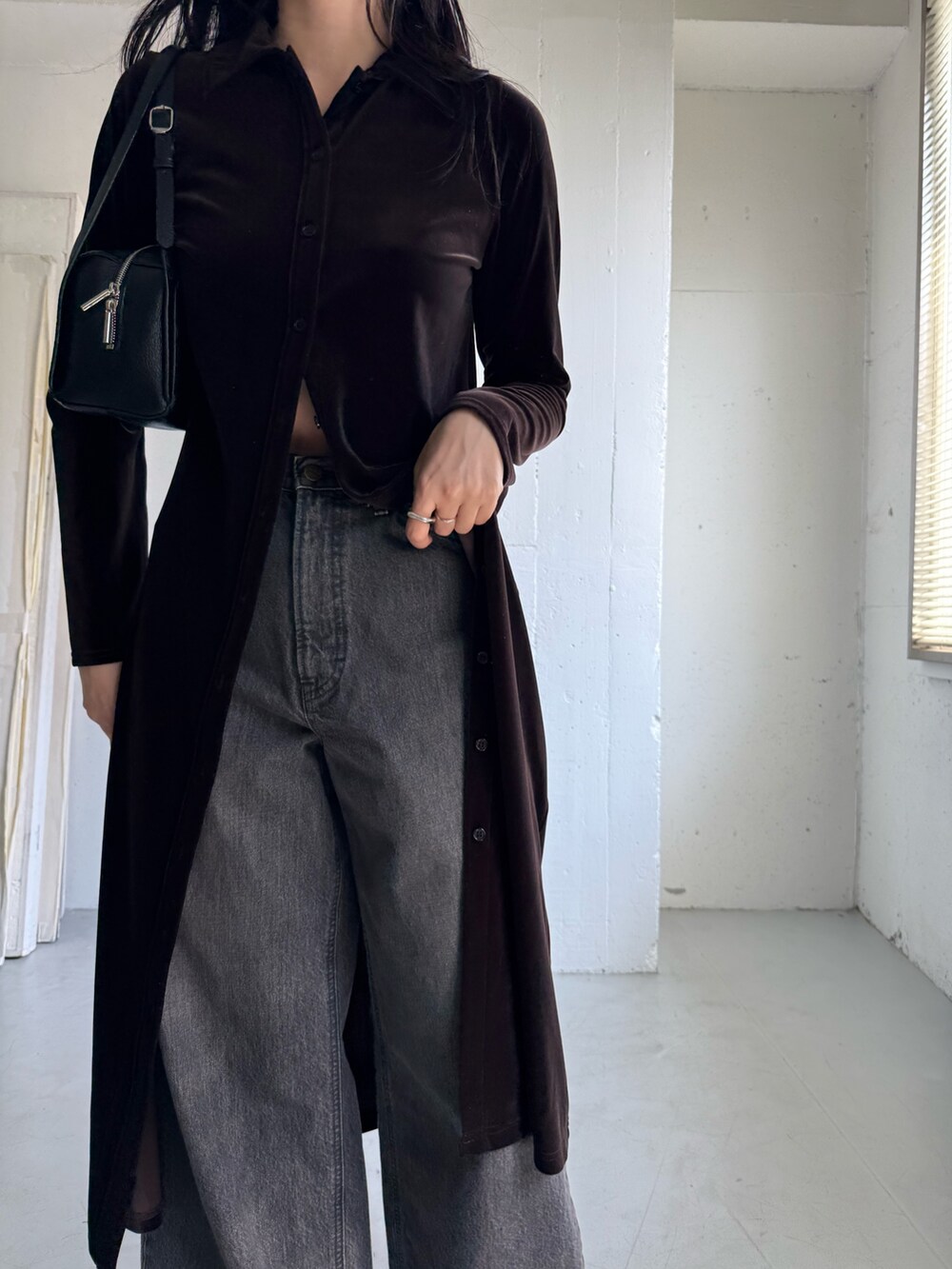 ブラック系のデニムパンツ、ブラウン系のワンピース、ブラック系のボストンバッグを着用したレディースの秋コーディネートの7枚目の写真