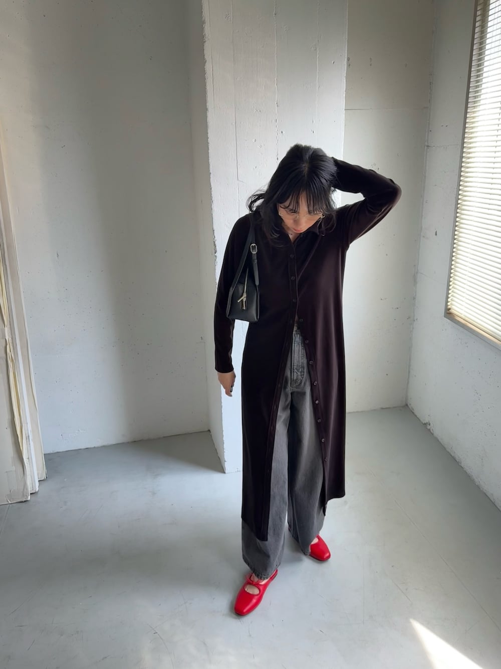 ブラック系のデニムパンツ、ブラウン系のワンピース、ブラック系のボストンバッグを着用したレディースの秋コーディネートの4枚目の写真