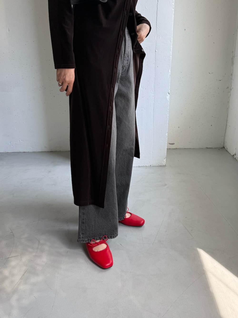 ブラック系のデニムパンツ、ブラウン系のワンピース、ブラック系のボストンバッグを着用したレディースの秋コーディネートの8枚目の写真