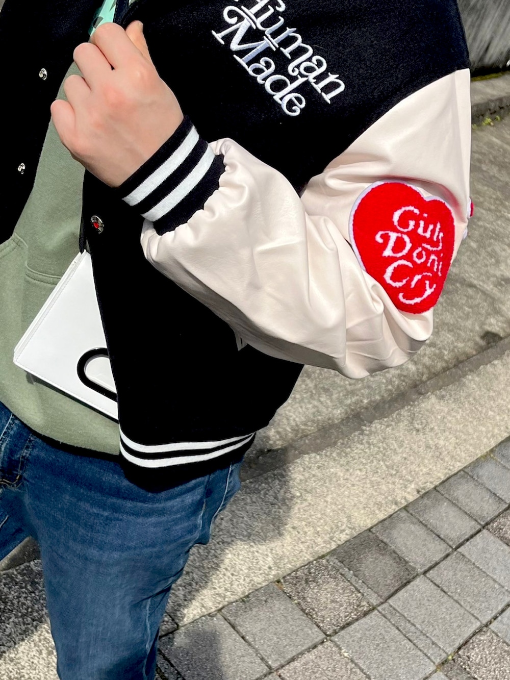 ブラック系のスタジャン、グリーン系のパーカー、その他のトートバッグを着用したメンズの春コーディネートの2枚目の写真