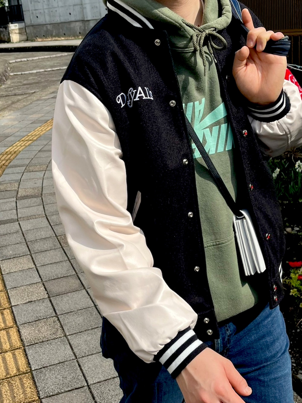 ブラック系のスタジャン、グリーン系のパーカー、その他のトートバッグを着用したメンズの春コーディネートの3枚目の写真