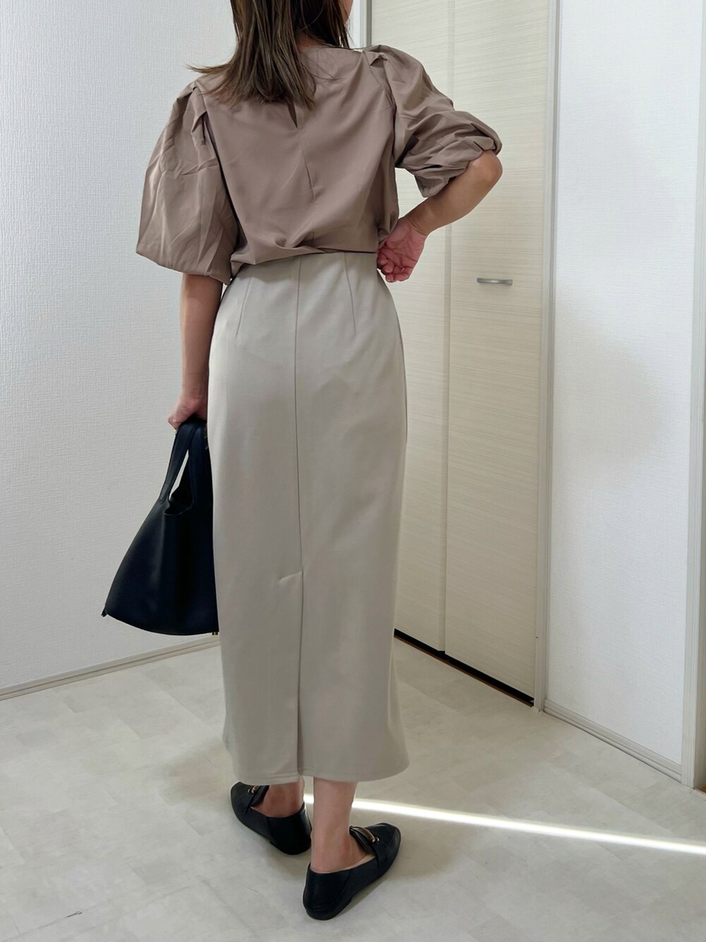 ベージュ系のTシャツ/カットソー、ブラック系のスカート、ベージュ系のスニーカーを着用したレディースの秋コーディネートの4枚目の写真