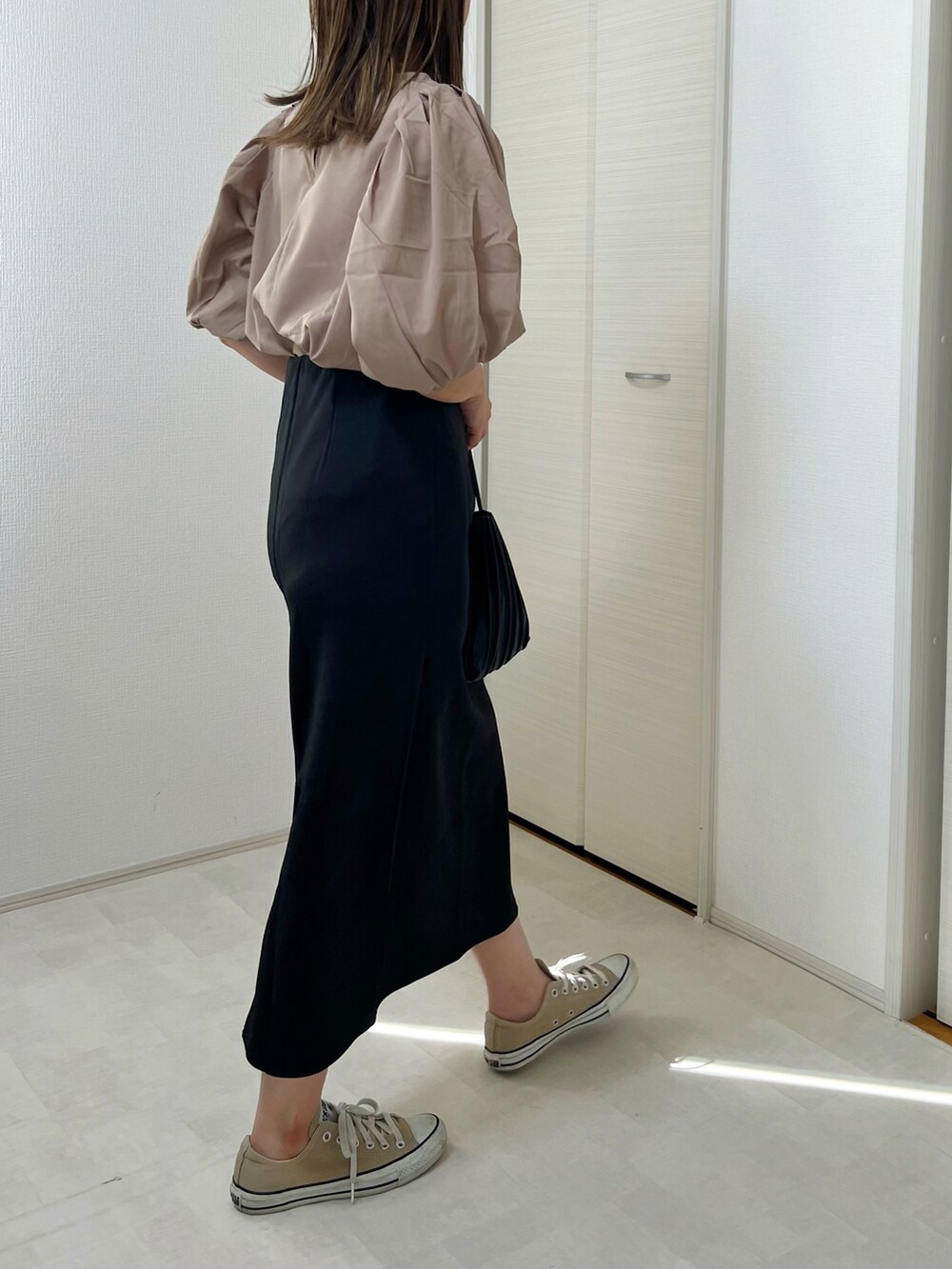 ベージュ系のTシャツ/カットソー、ブラック系のスカート、ベージュ系のスニーカーを着用したレディースの秋コーディネートの2枚目の写真